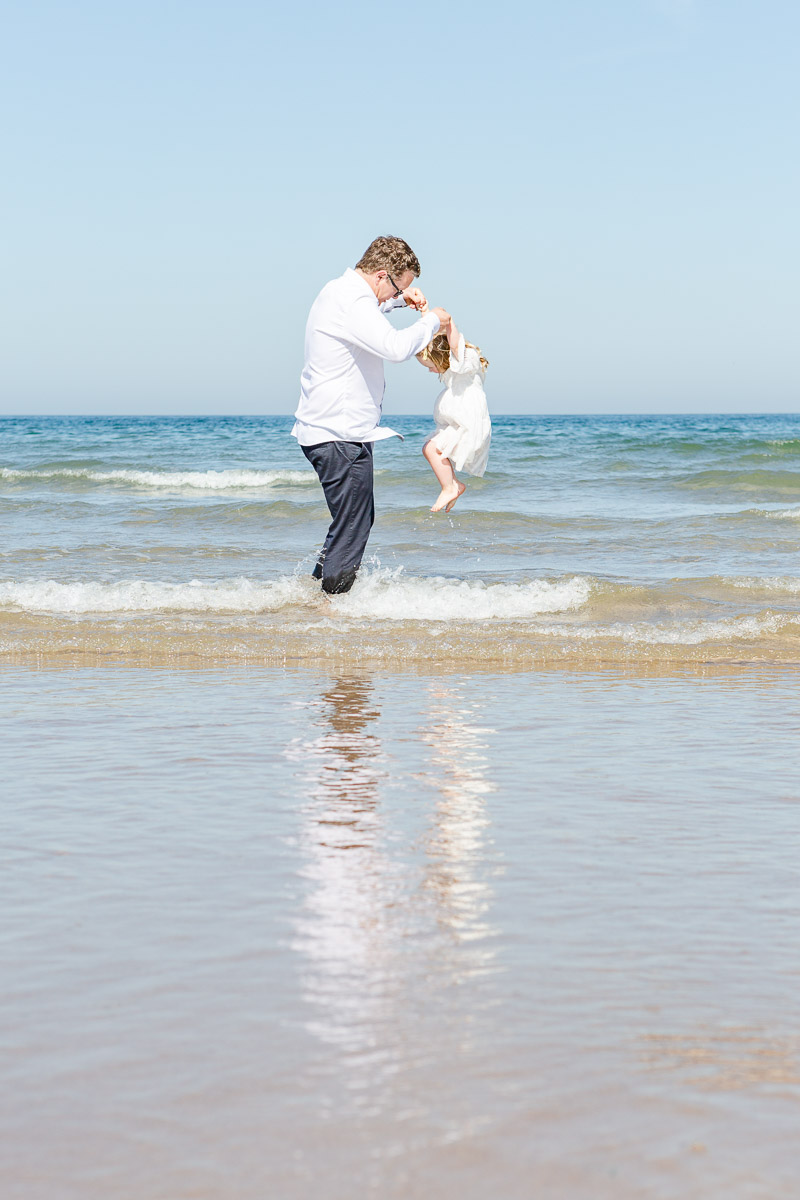 Daddy lifting daughter over waves