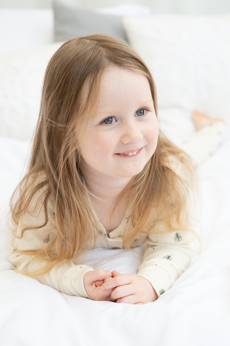 little girl in Christmas pyjamas smiling at camera