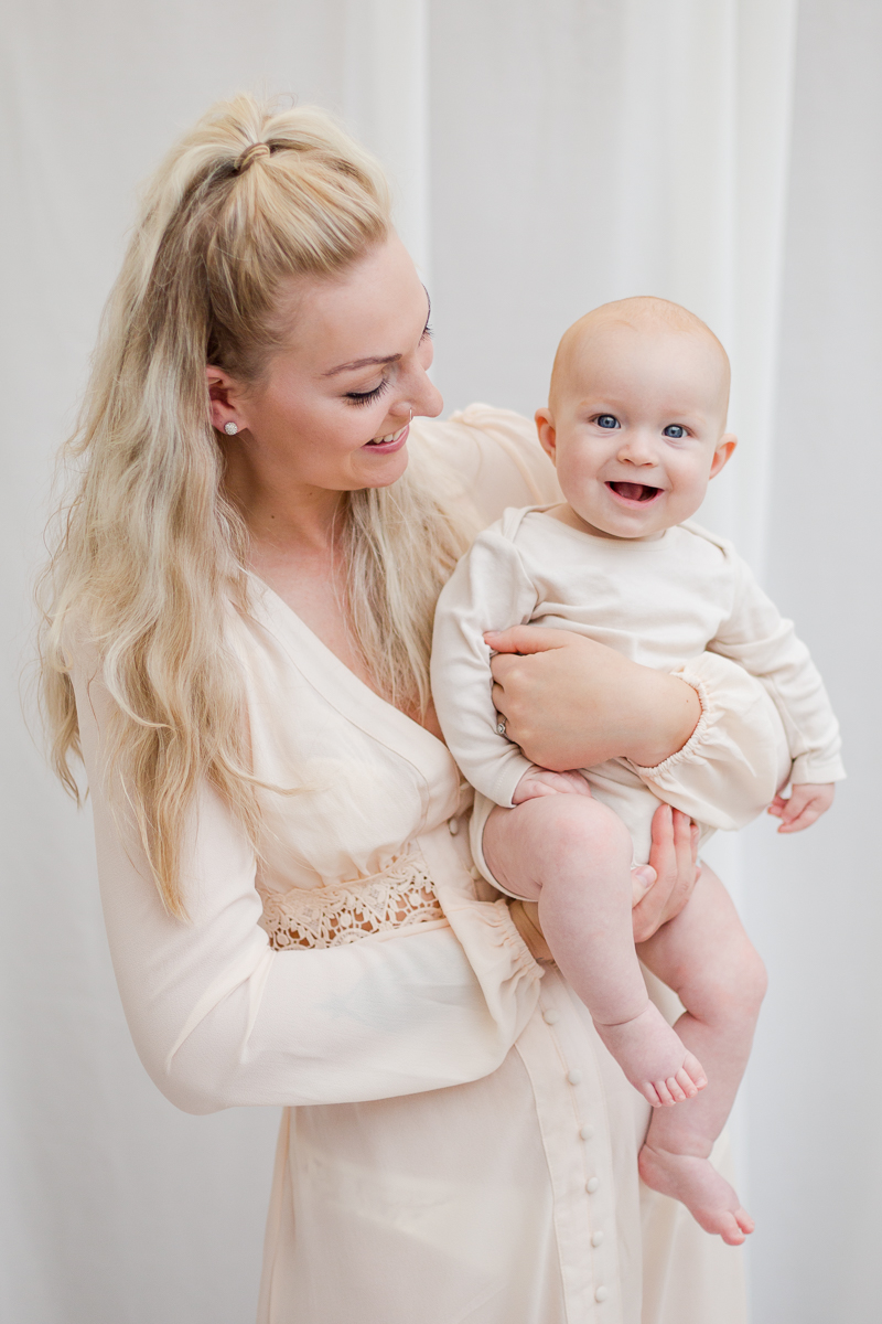 baby and me photography session mummy holding daughter to smile at camera while smiling at baby