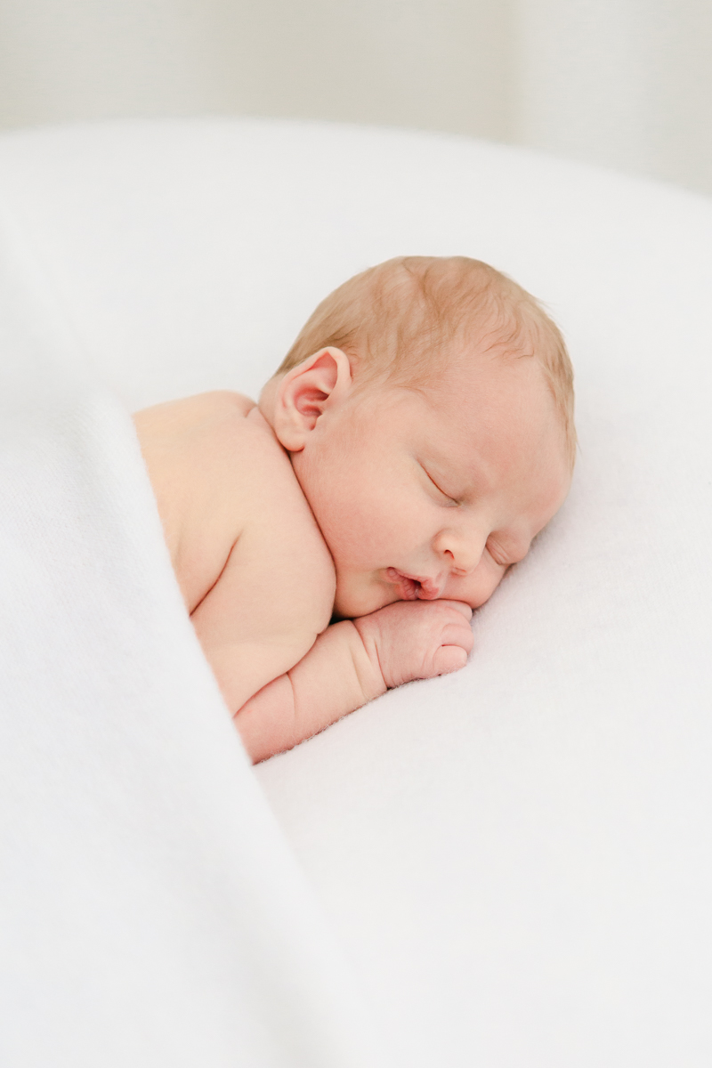 sleeping baby asleep on white blanket wrapped in white