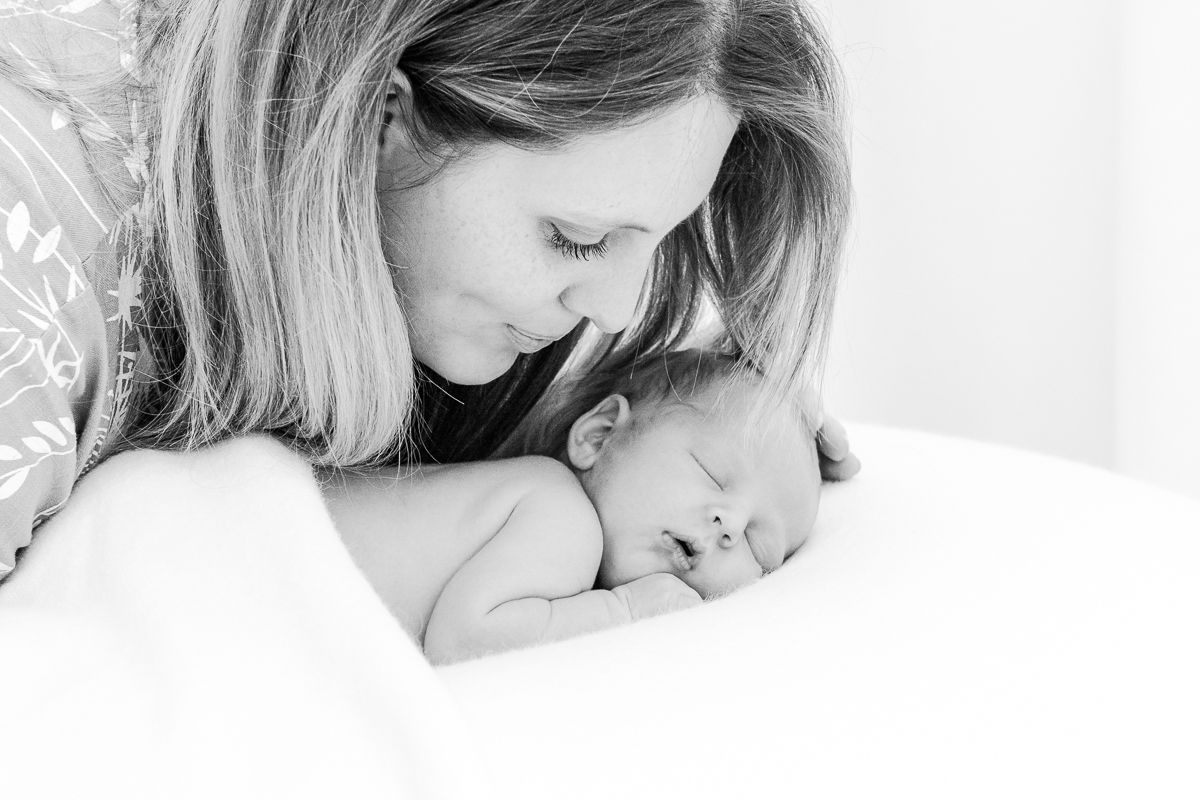 black and white photo of loving mummy smiling at sleeping baby