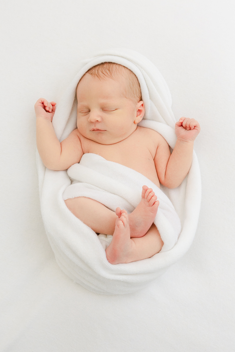 sleeping newborn baby wrapped in white blanket