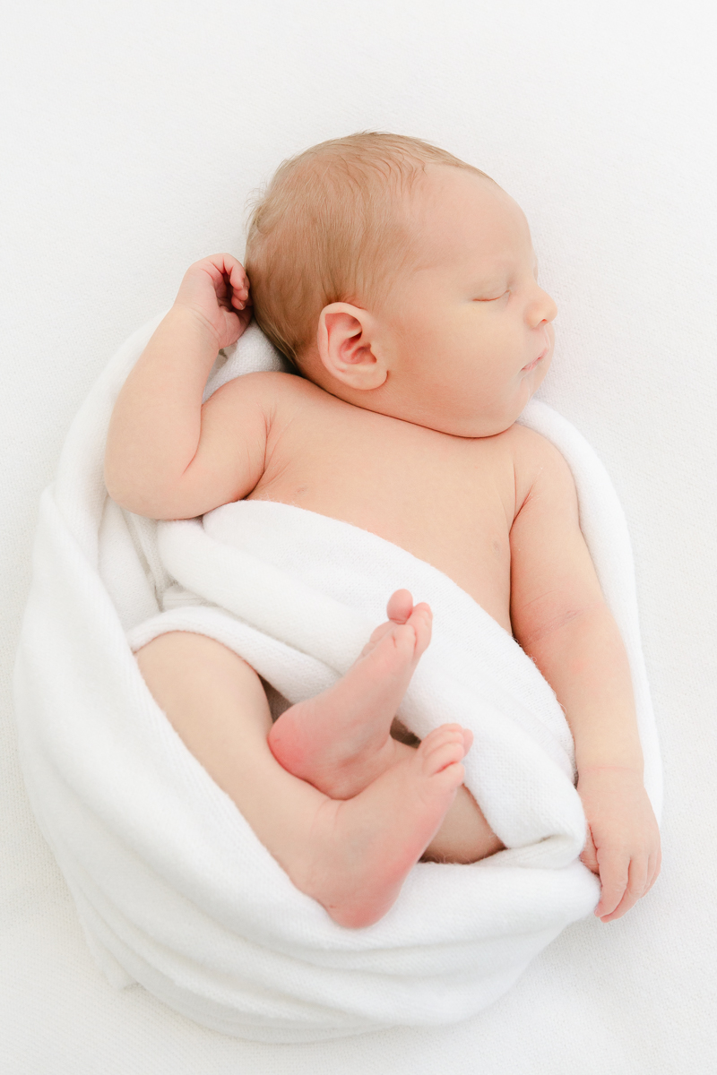 newborn baby cocooned in white wrap asleep