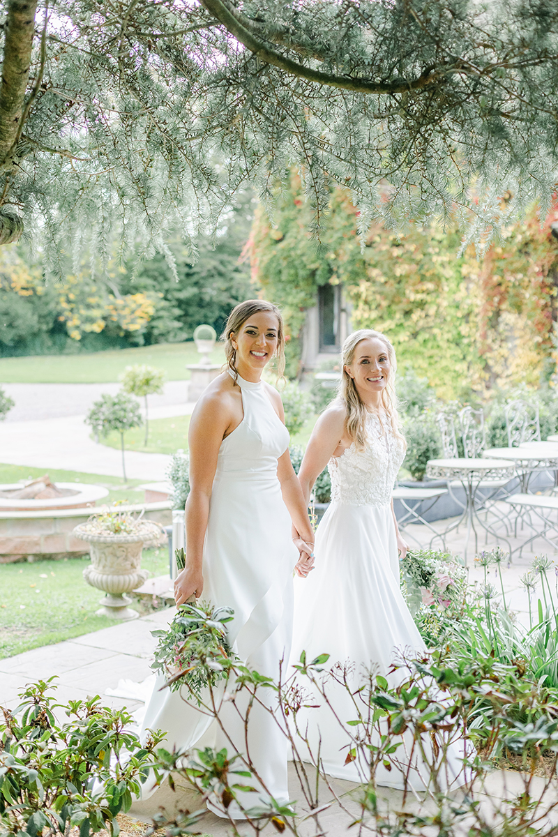 two brides holding hands through trees