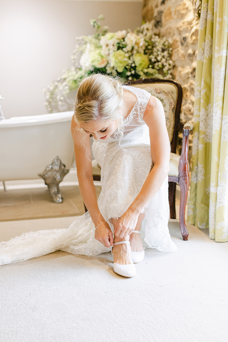 bride fastening her wedding shoes