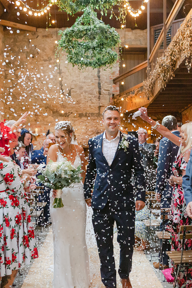 bride and groom waling through confetti