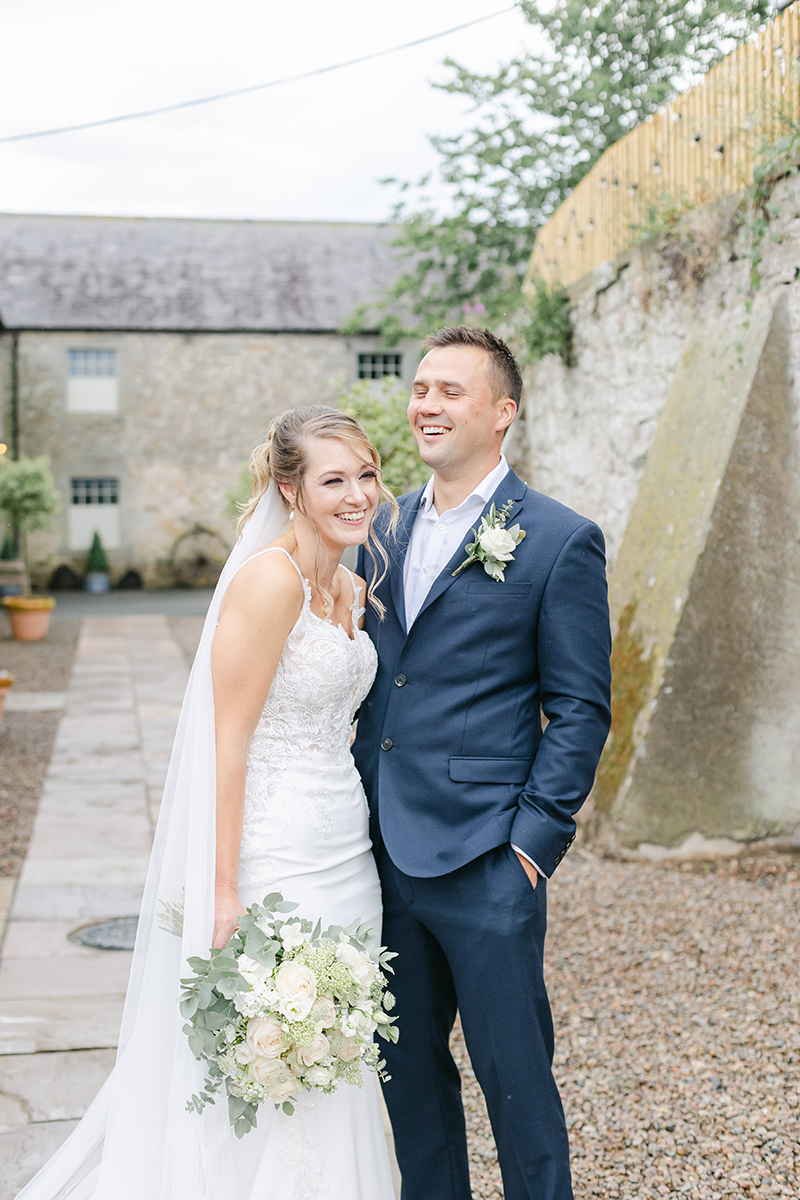 Bride and groom laughing outside venue