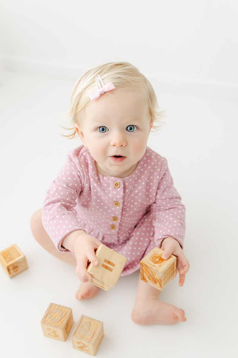 little toddler in pink holding wooden blocks