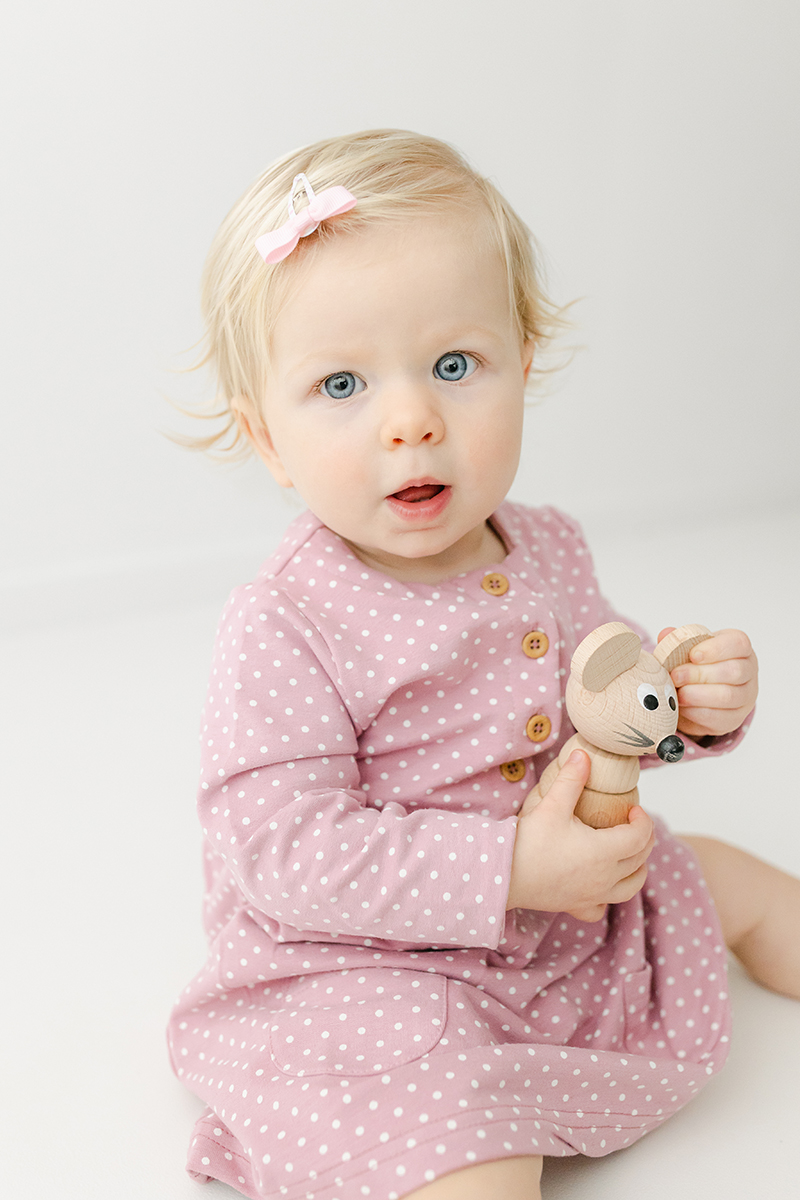 little girl in pink holding wooden mouse