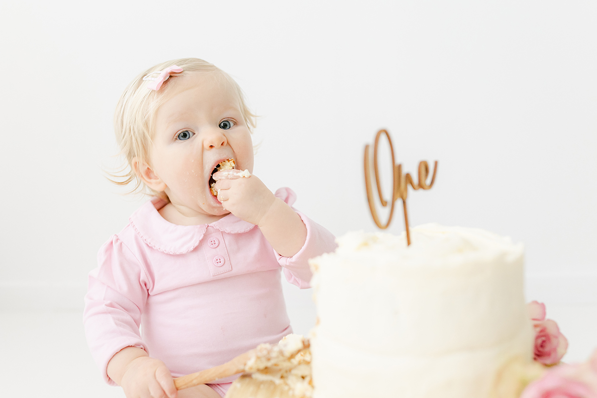 little girl eating 1st birthday cake