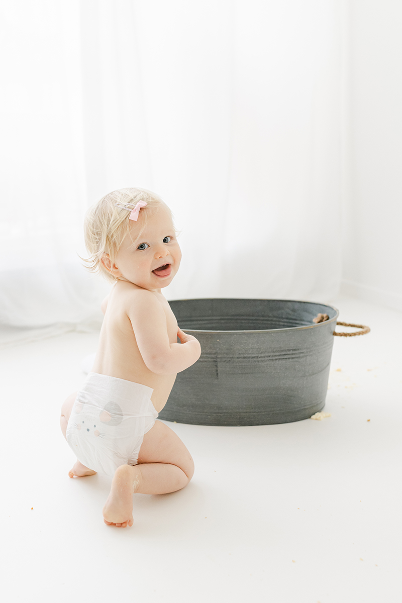 little girl in nappy smiling back at camera ready for tin bath