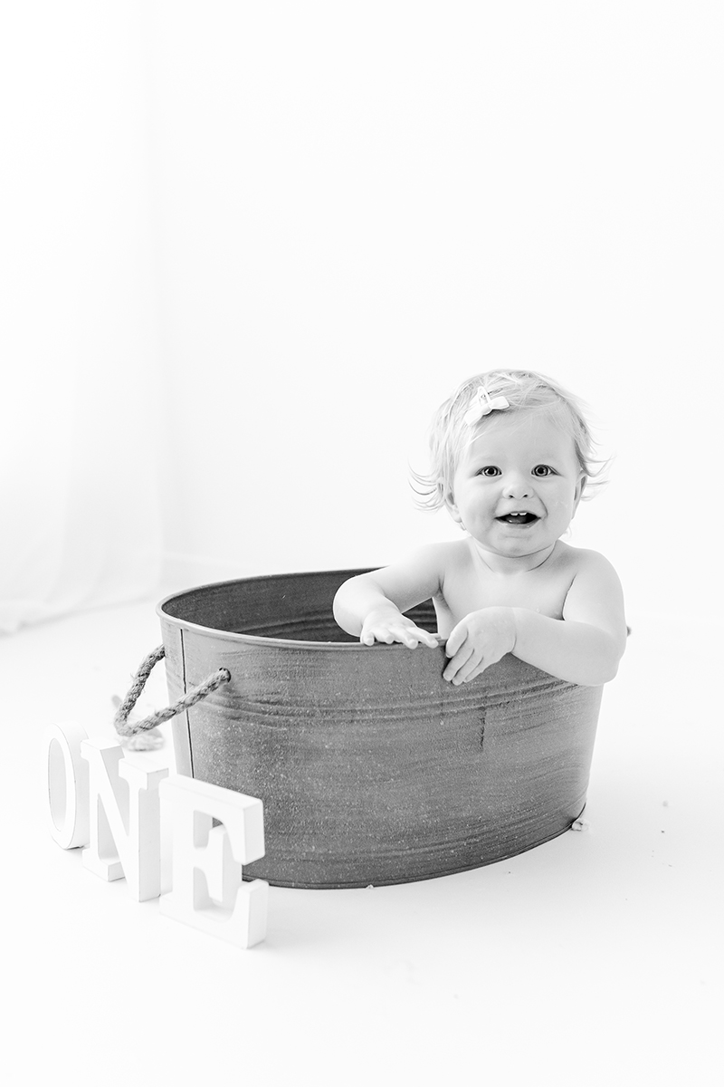 little girl in tin bath tub with letter ONE in front