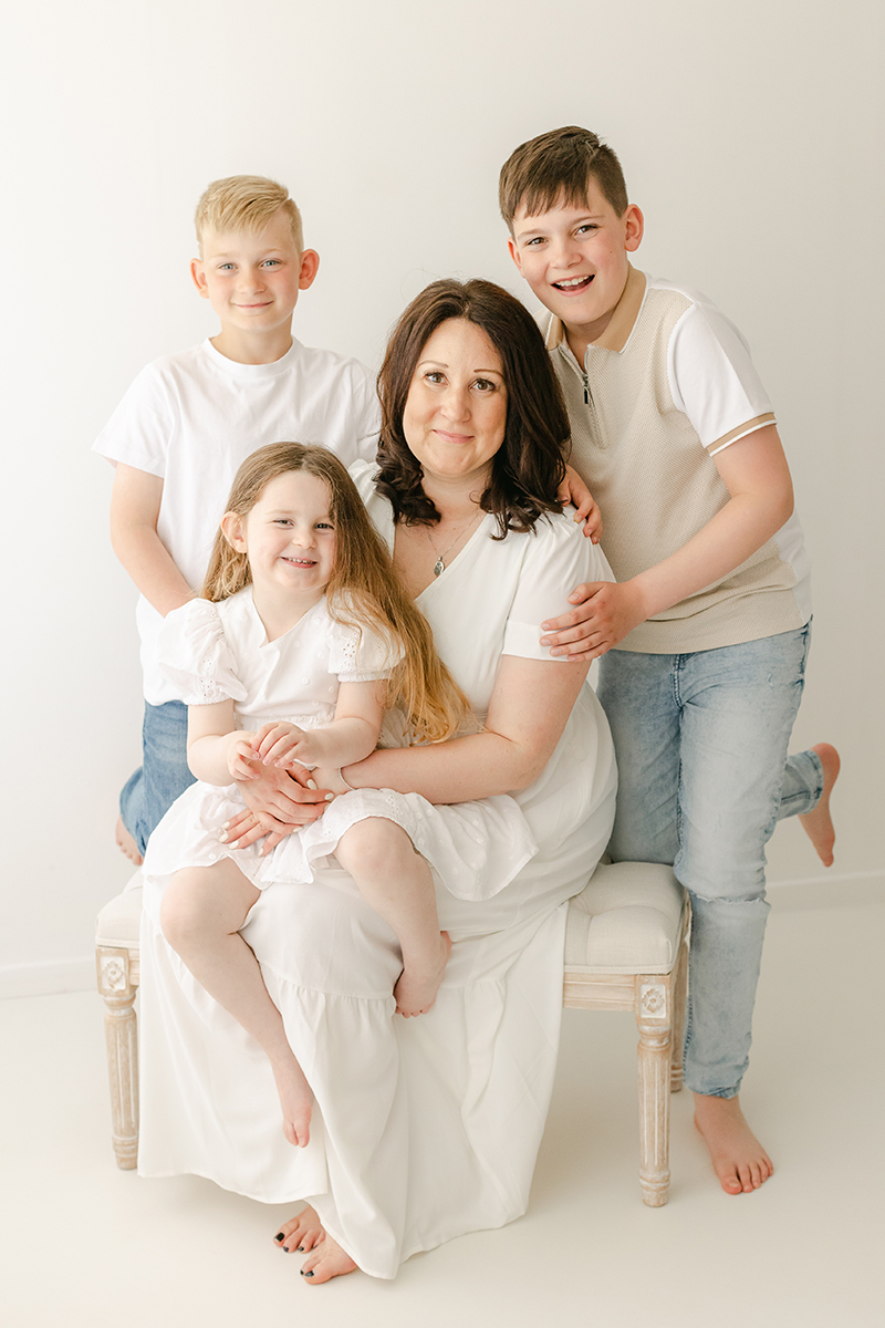 mum and three children sat on bench in photo studio