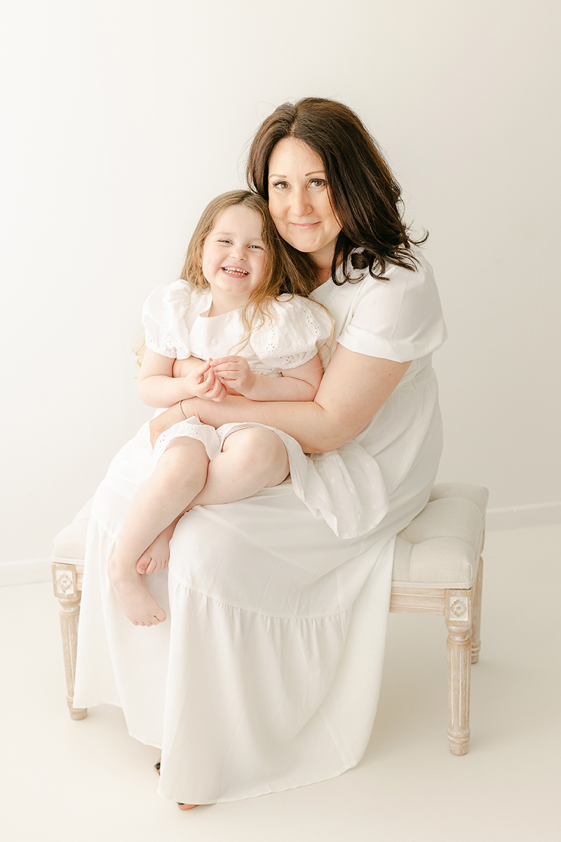 mum and daughter sat on bench in photo studio