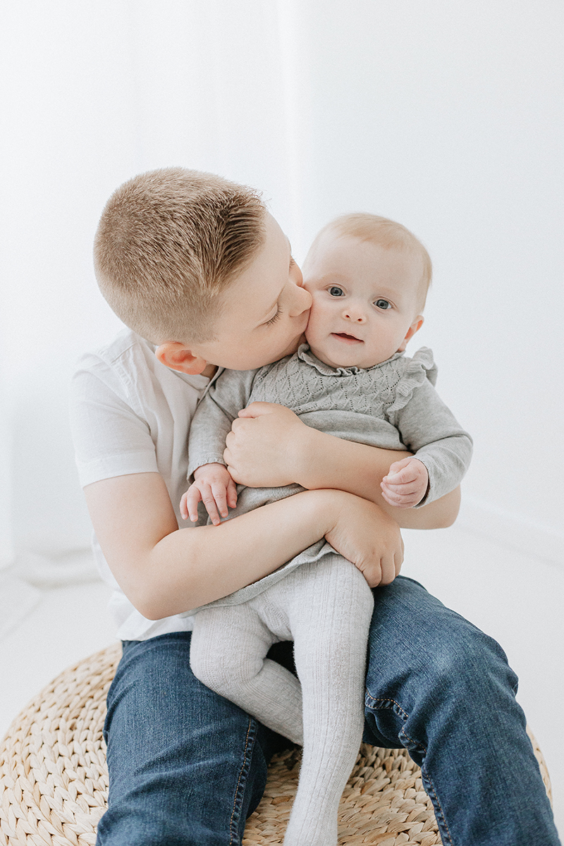 brother kissing baby sister on cheek