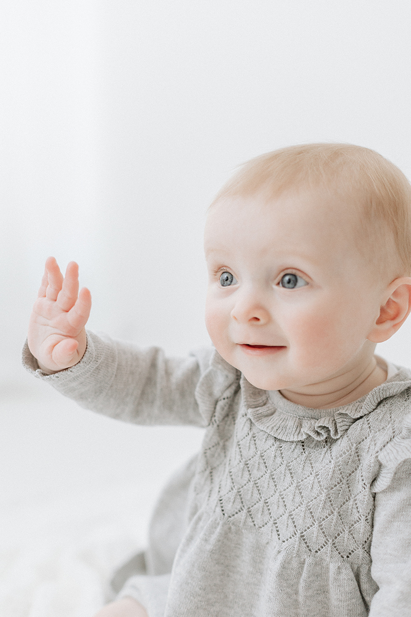 little baby sitting up and waving