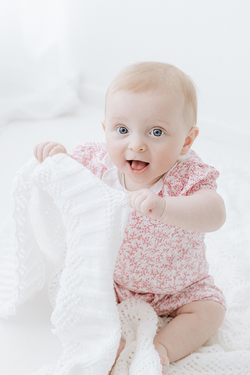 little baby sitting and playing with blanket