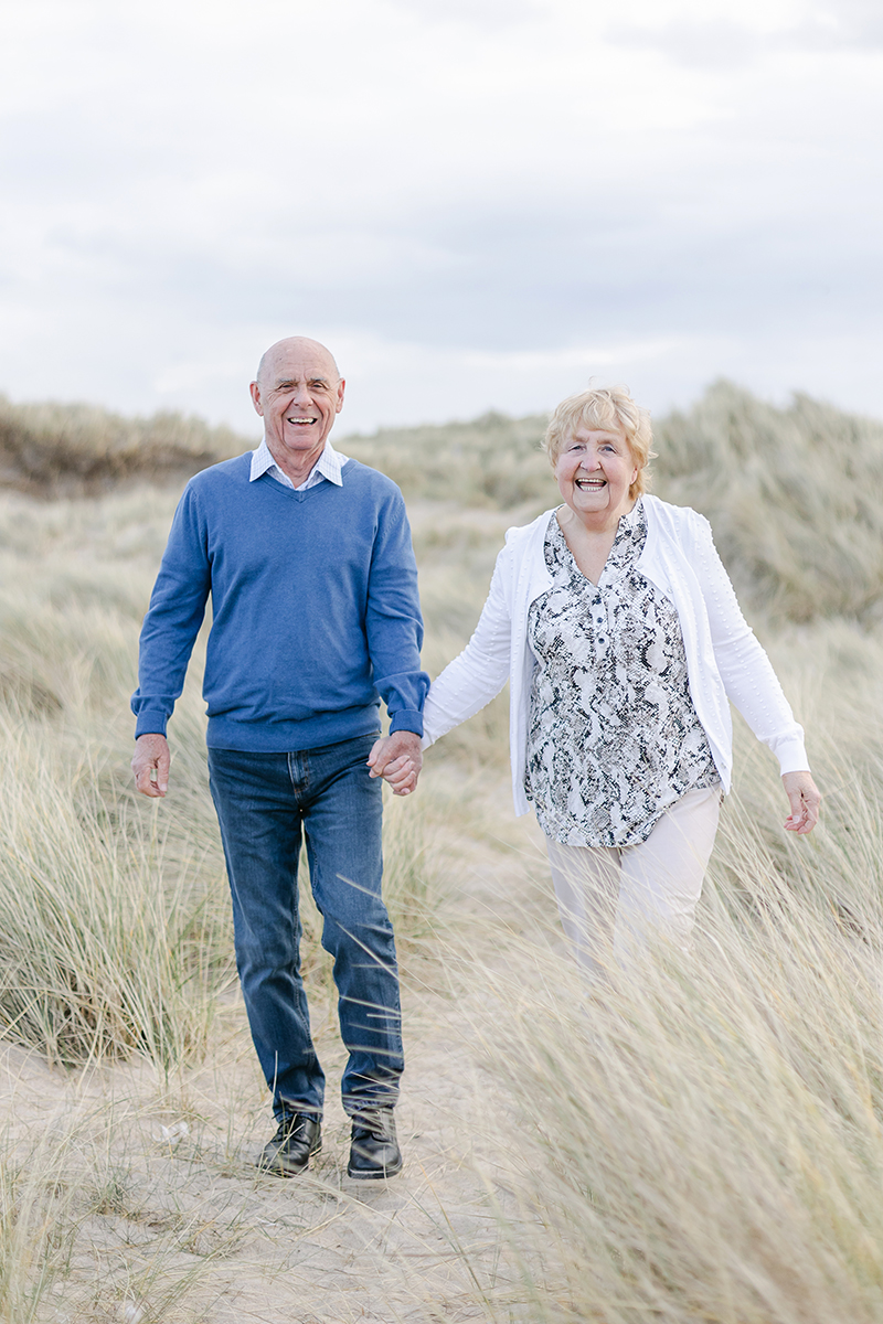 Grandparents walking through dune grasses