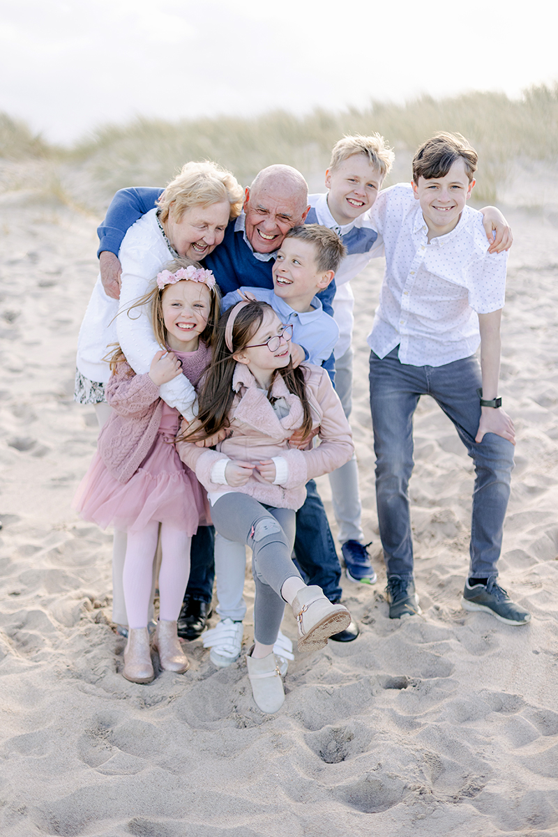 grandparents hugging grandchildren on beach