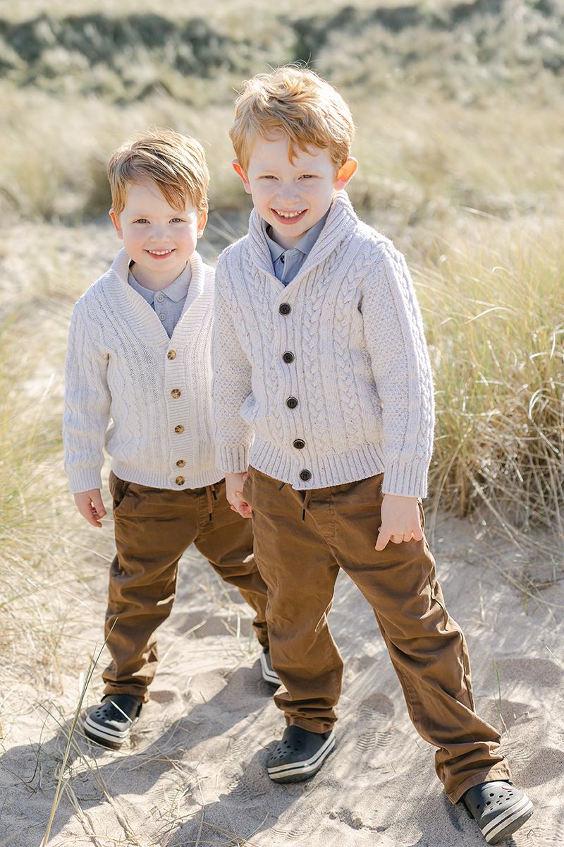 young brothers smiling at camera in dunes for family photo shoot