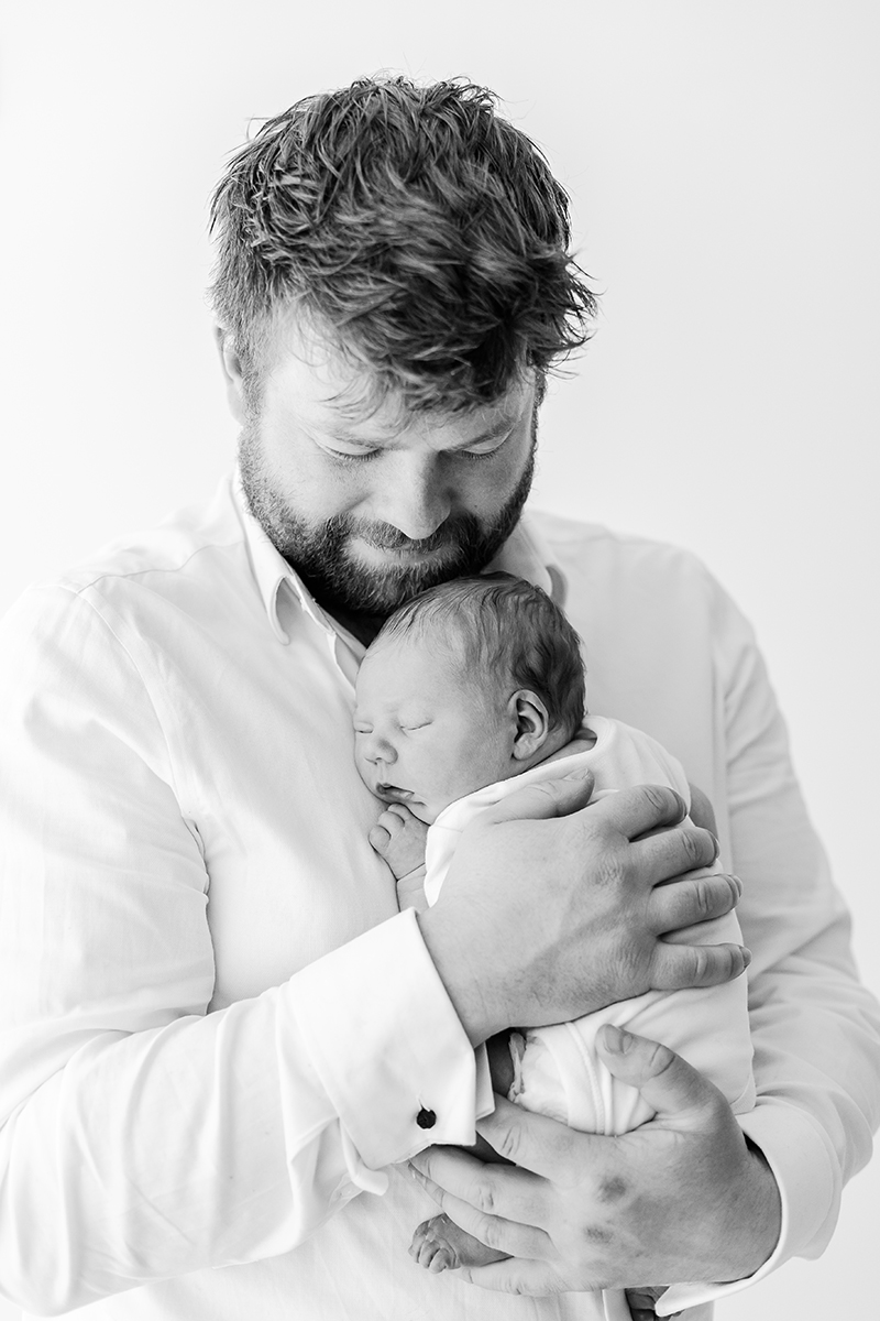 dad cuddling newborn black and white