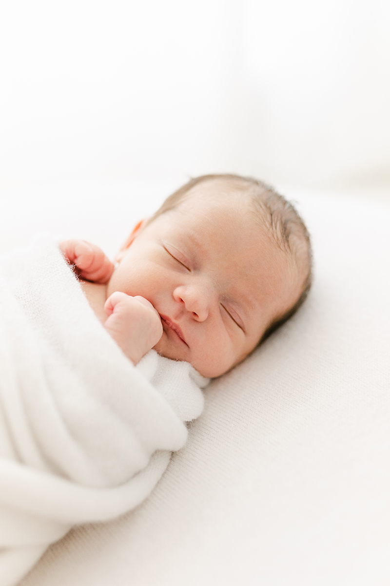 newborn wrapped in white blanket asleep