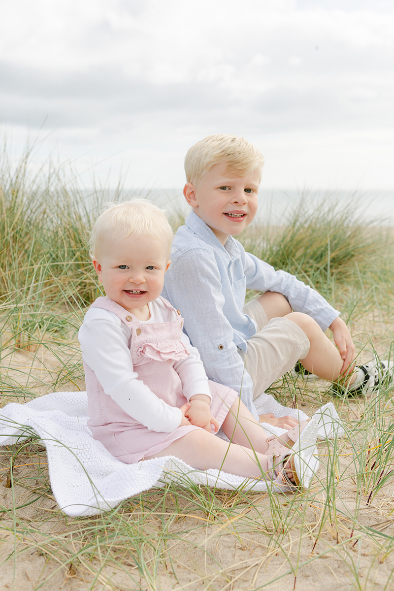 young brother and sister smiling at camera on dunes