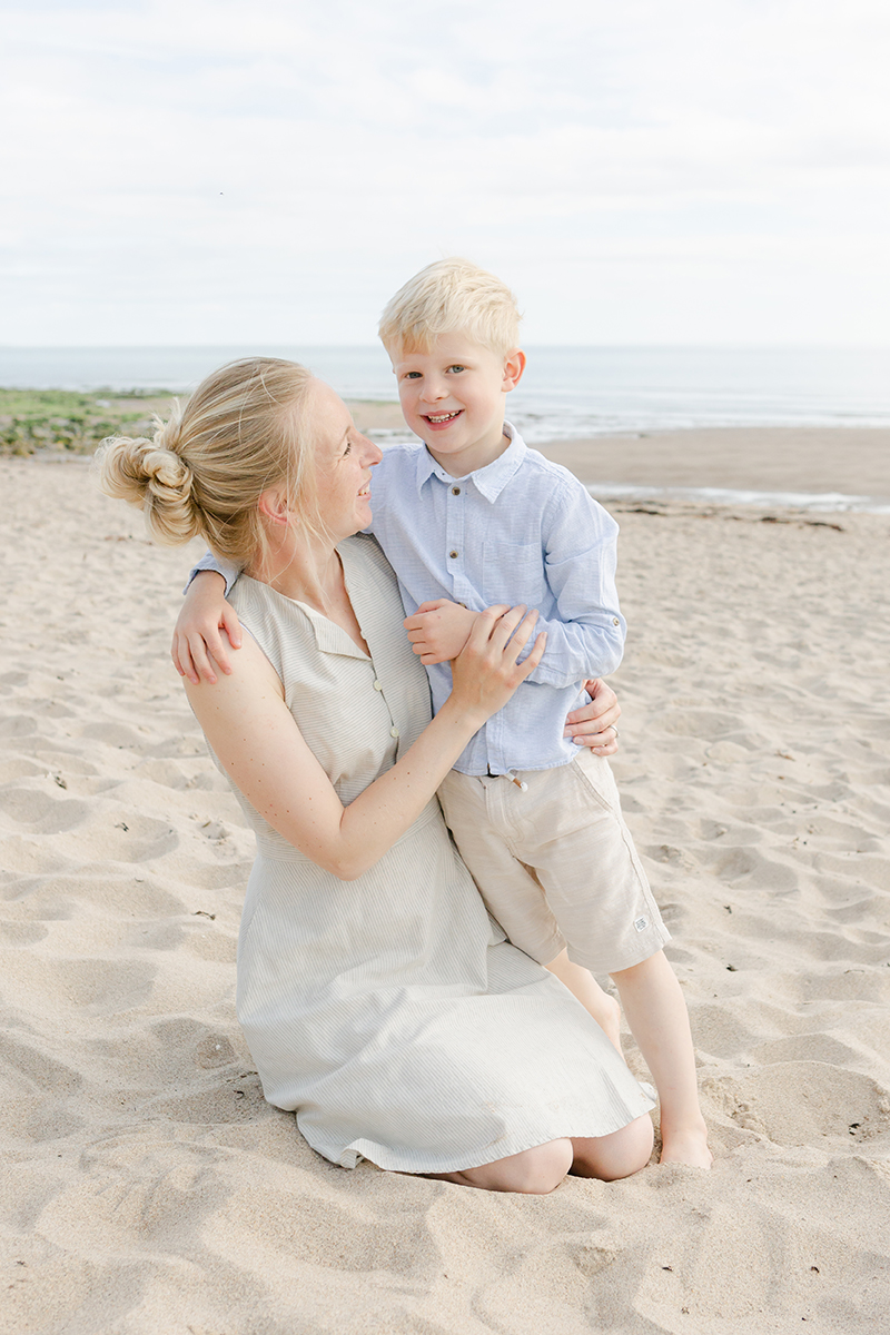 mum and son on beach hugging for camera