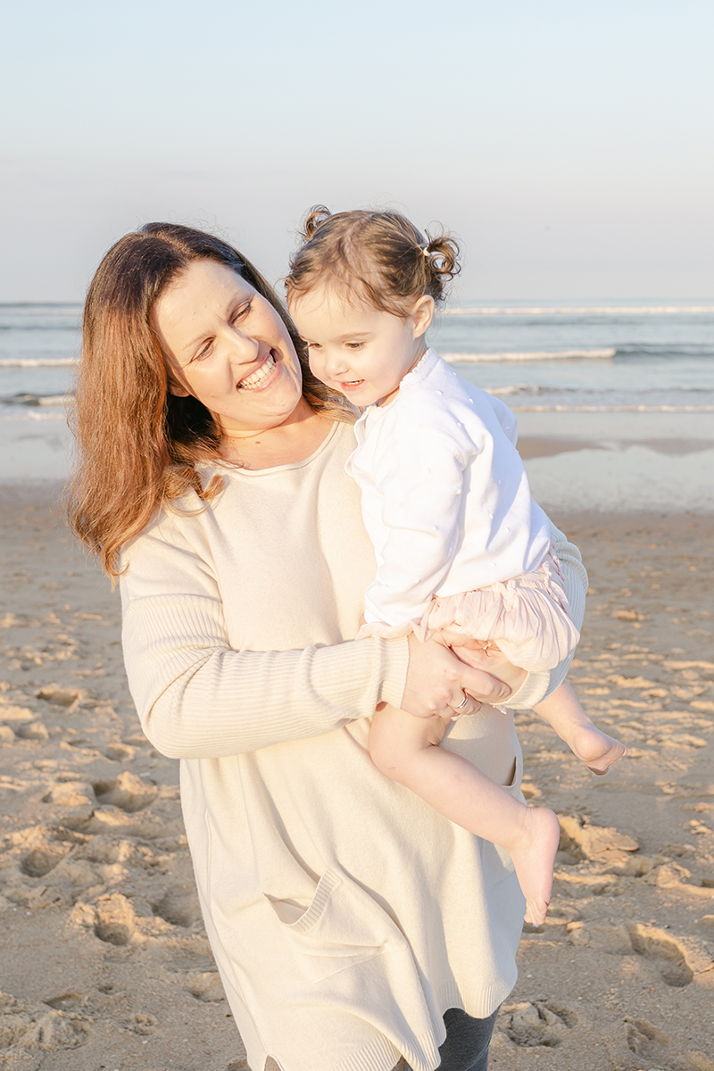 mum smiling at toddler in arms on beach