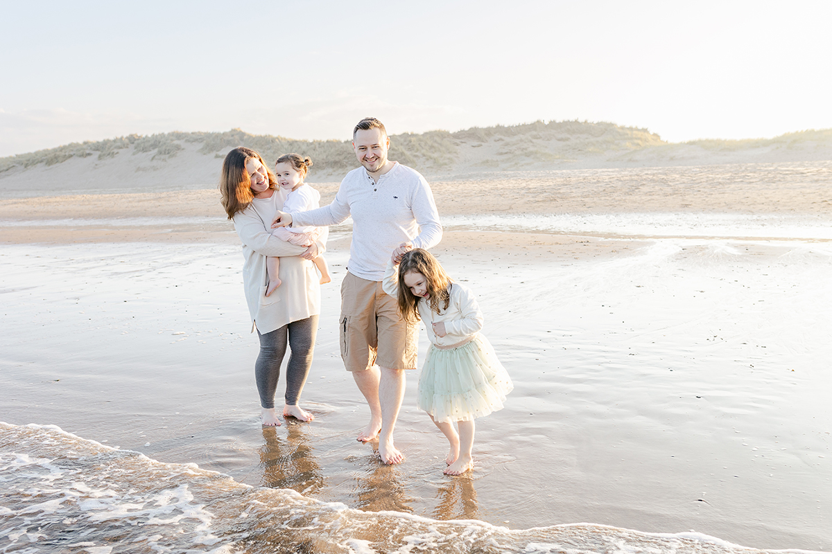 family of four paddling in the sea for family photo shoot