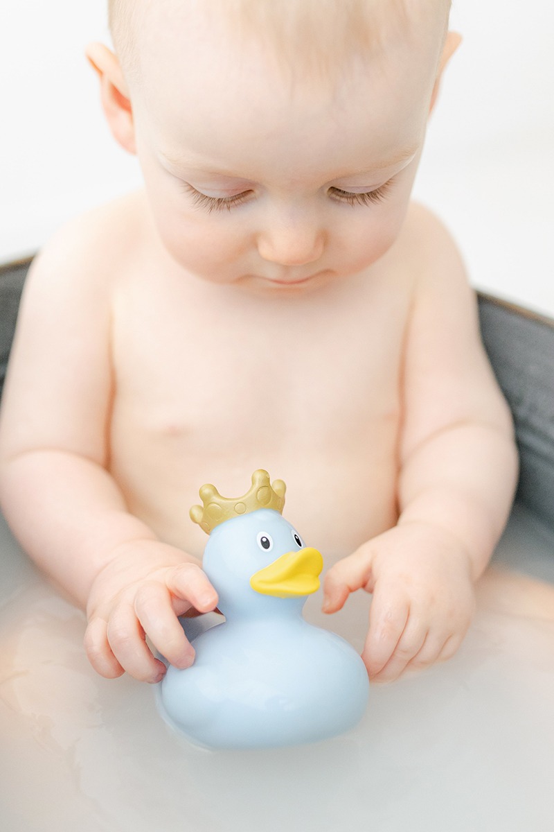 little boy in tin bath holding blue rubber duck