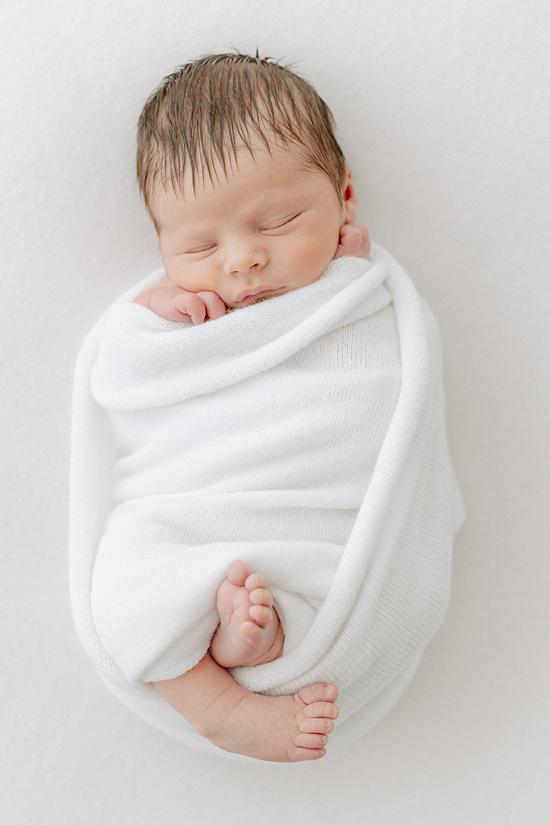 little baby wrapped in white for newborn photo shoot