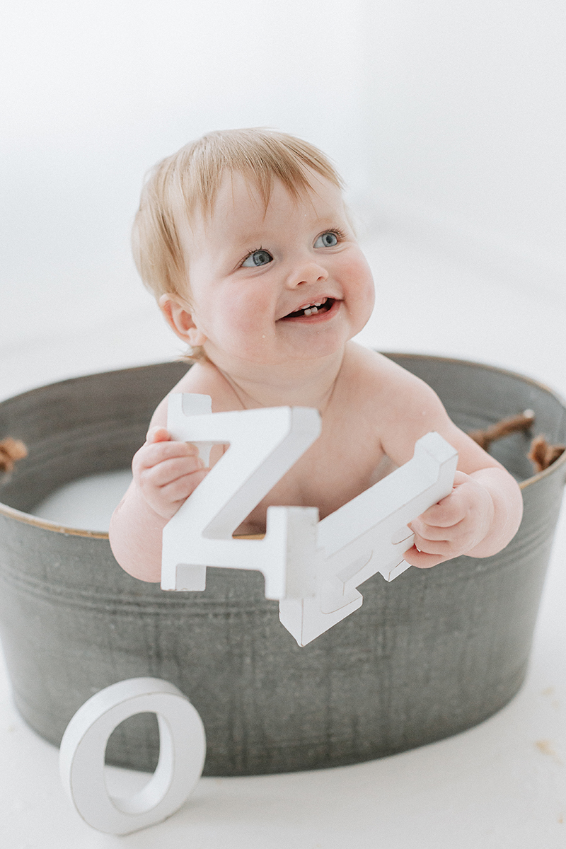 toddler in tin bath playing with ONE letters