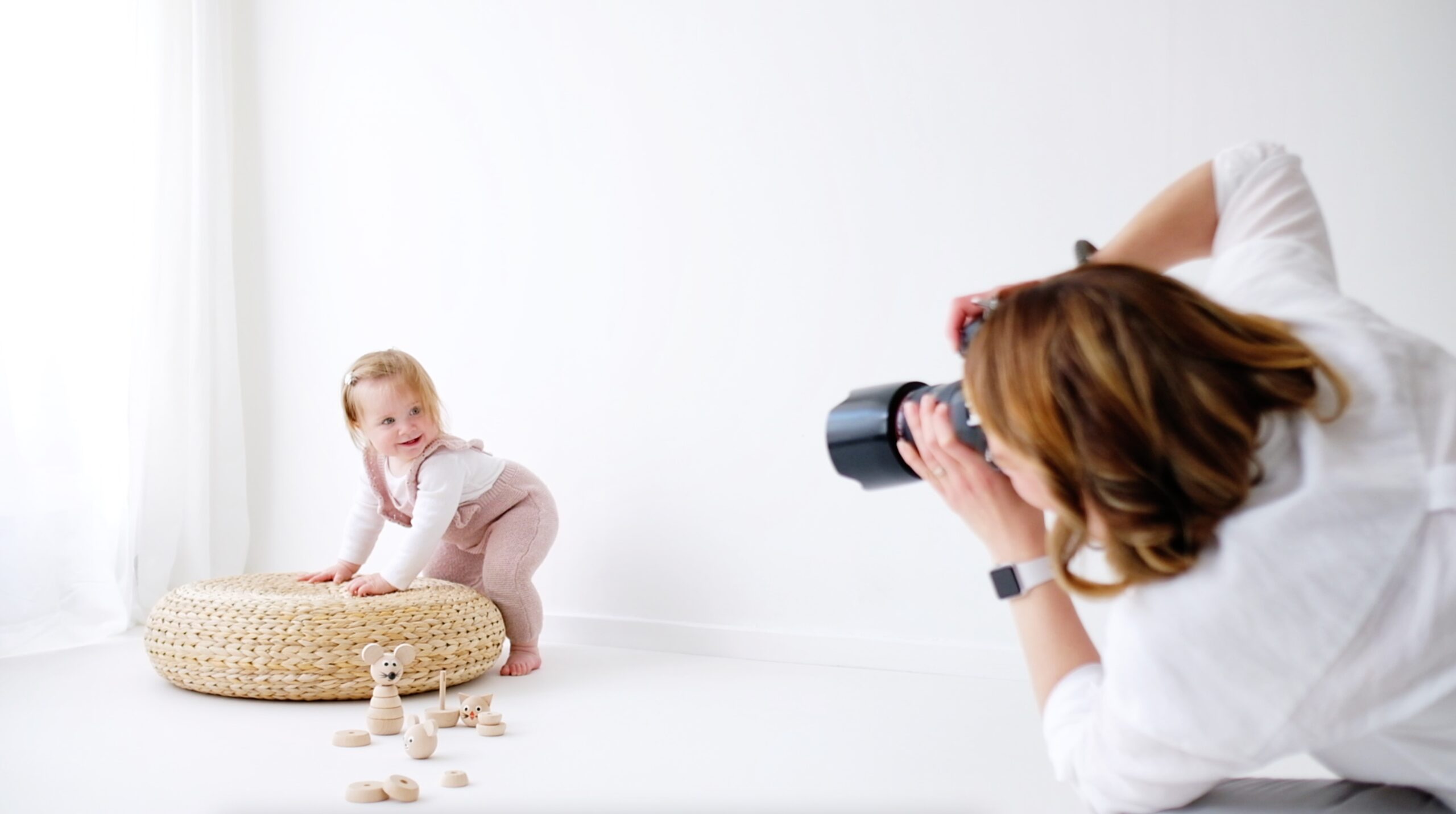 photographer in studio photographing little girl in pink